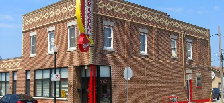 A two-story brick restaurant building on a street corner in Overland Park, Kansas, with a decorative diamond brickwork band under the roofline, large ground-floor windows and a tall vertical sign on the corner, under a clear blue sky