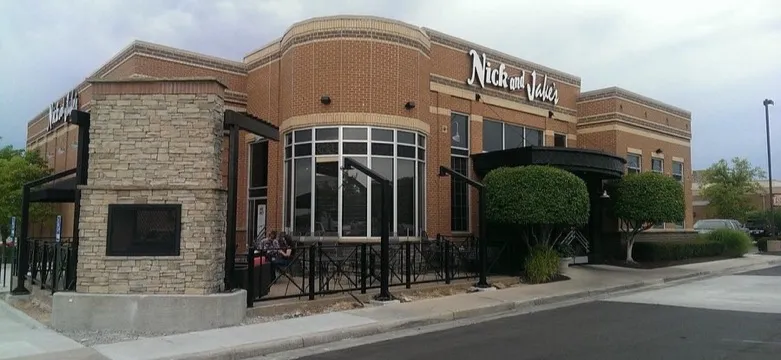 A brick restaurant building with a rounded glass corner, a stone fireplace tower and a covered patio on a street corner in Overland Park, Kansas