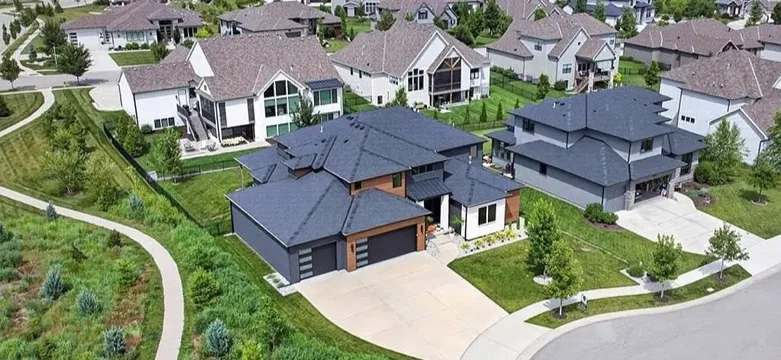 An aerial view of a suburban neighborhood in Overland Park, Kansas, with new two-story homes, a curving street, a walking path and green open space