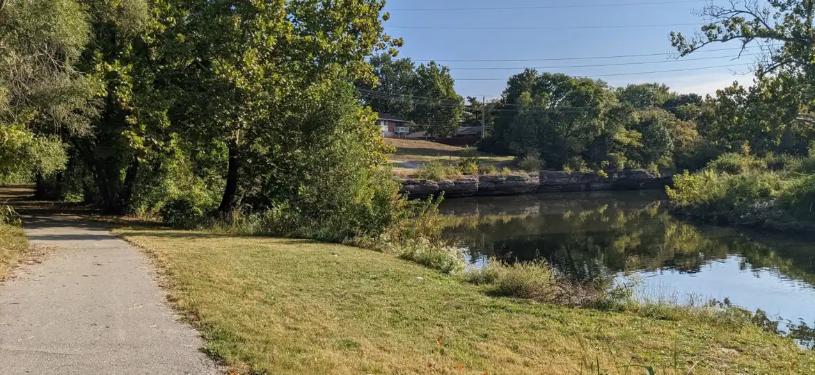 Indian Creek Trail, Overland Park, Kansas: a paved trail through trees beside a creek with a rock-lined bank