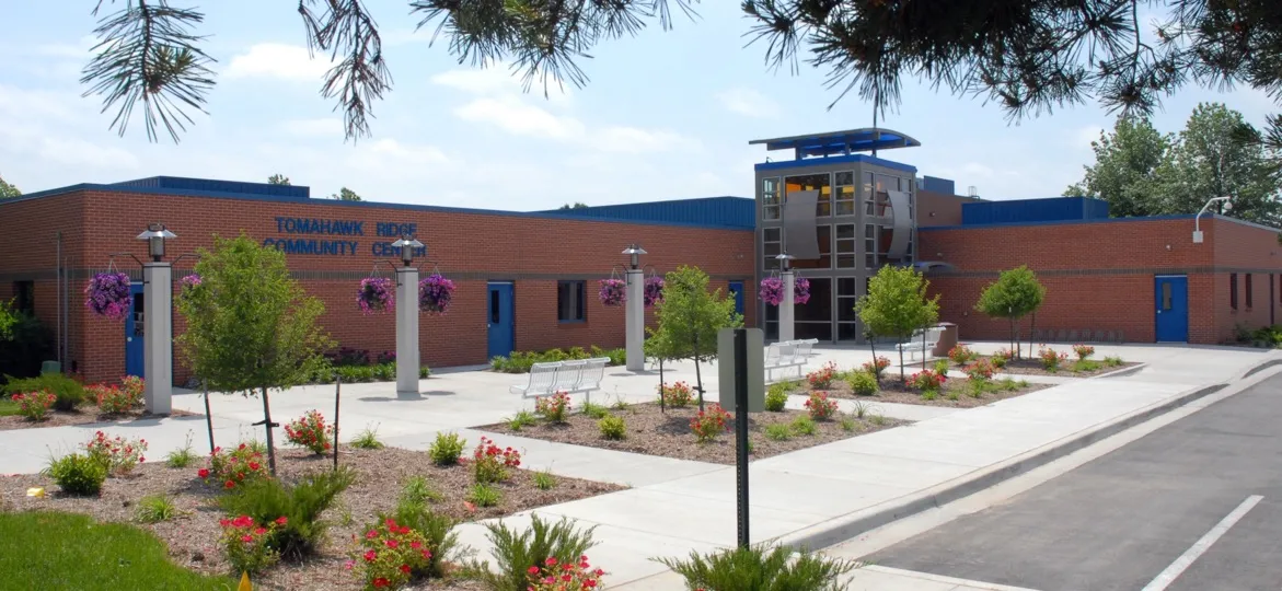 Tomahawk Ridge Community Center, Overland Park, Kansas: the brick building with a glass tower, with a walkway and flower beds in front
